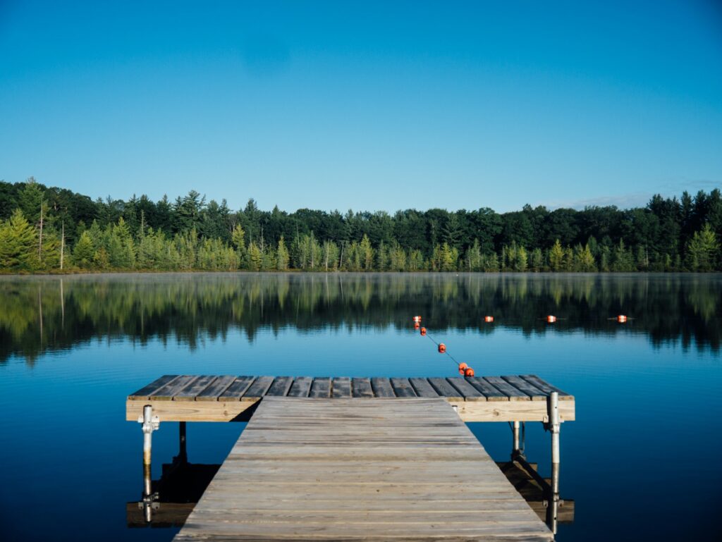 A calm lake at dawn seen from a wooden dock